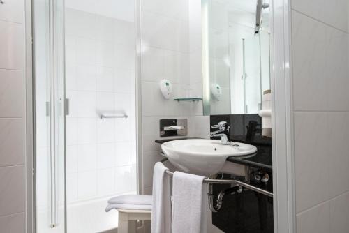 德绍利奥波德王子丽笙酒店的白色的浴室设有水槽和淋浴。