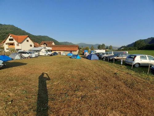 古察Dragacevska avlija - Camp的站在帐篷的田野上的一个人的影子