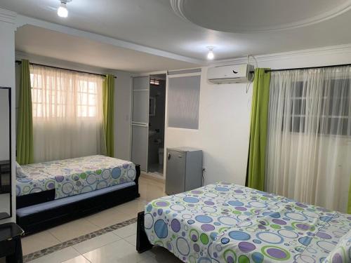 圣安德烈斯Posada Cocos Place的一间卧室设有两张床和绿色窗帘
