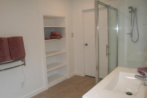OkoroireBridgehaven Guesthouse的带淋浴和盥洗盆的白色浴室