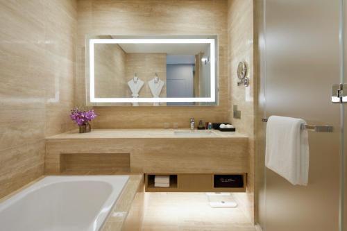 西归浦市济州神话世界度假酒店 – 蓝鼎的带浴缸、水槽和镜子的浴室