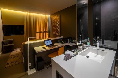 尼亚美Noom Hotel Niamey的一间带水槽的浴室和一张带笔记本电脑的书桌