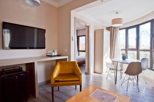 马拉喀什Amani Hotel Suites & Spa的客厅配有电视和桌椅