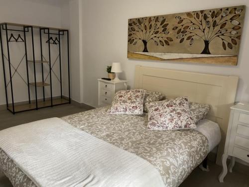 塞维利亚WISH SUITE NIEBLA DE SEVILLA的卧室配有一张床,墙上挂有绘画作品