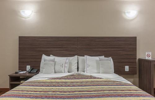 贝廷阿巴酒店的一间卧室配有一张大床和木制床头板