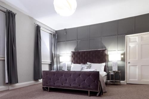 莱斯特城市客房酒店的一间卧室配有一张带大型黑色床头板的床