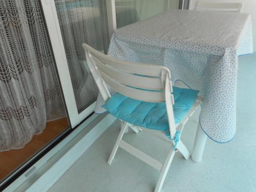 安德诺莱斯贝恩T2 Bassin d'Arcachon, 100m plage, centre-ville的一张白色椅子,坐在一张桌子旁,配有蓝色垫子