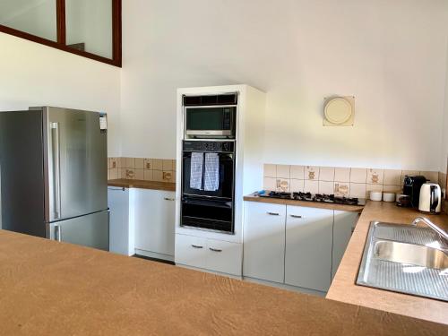 金斯科特Beachside House的厨房配有白色橱柜和不锈钢用具