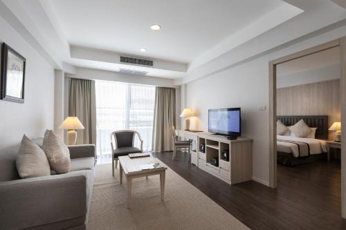 是拉差Classic Kameo Hotel and Serviced Apartments, Sriracha的酒店客房设有沙发、床和电视。