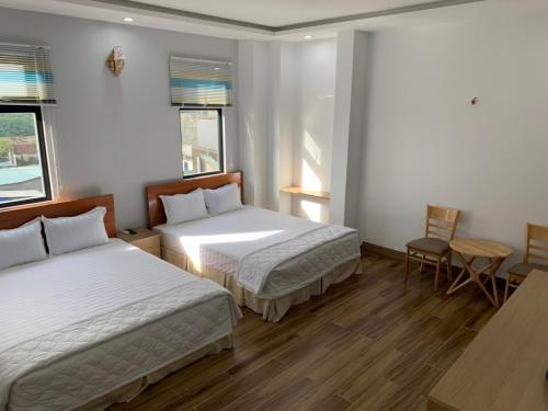 绥和市Hotel Hiệp Thành的一间卧室配有两张床和一张桌子及椅子