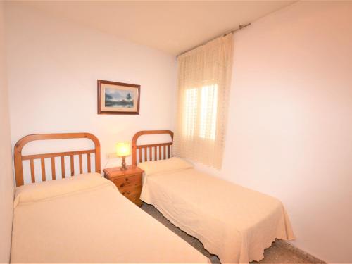 卡拉费尔Villa Service - Lindamar 1º 2ª的一间卧室设有两张床和一张桌子上的台灯。