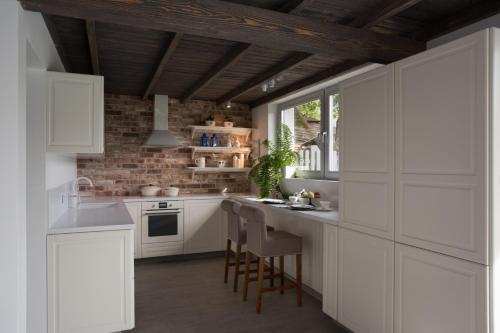 扎甘LEA Barn的厨房配有白色橱柜和砖墙