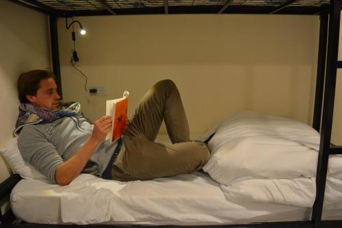 杰里科MOUNT41 Hostel的躺在床上看书的人