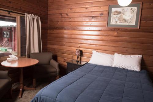 贾斯珀Miette Hot Springs Bungalows的卧室配有1张床、1张桌子和1把椅子
