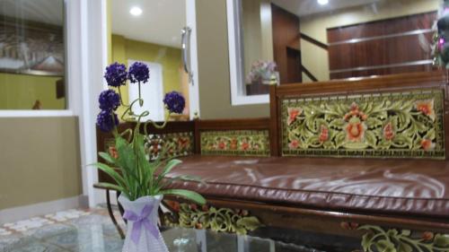 帕卢GRANADA INN PALU的一间卧室,配有带紫色花瓶的长凳