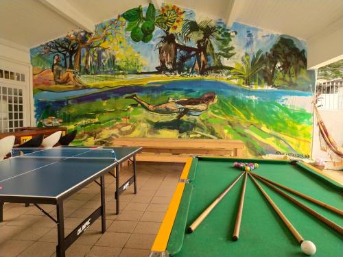 弗洛里亚诺波利斯Pequi hostel的一间设有两张乒乓球桌和壁画的房间