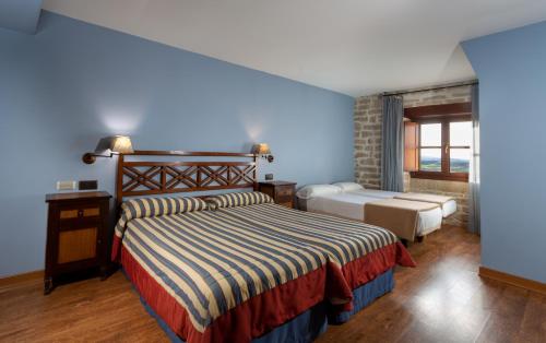 比亚纳Palacio de Pujadas by MIJ的一间卧室设有两张床和蓝色的墙壁