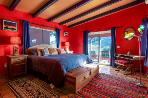 二十九棕榈村Chuck's Cabin in a Joshua Tree Community的一间卧室设有红色的墙壁、一张床和一张书桌
