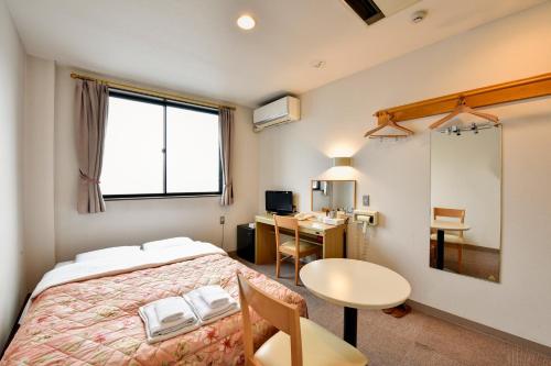 高山哈娜酒店的一间卧室配有一张床、一张桌子和一张书桌