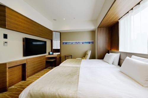 东京remm plus Ginza的酒店客房设有两张床和一台平面电视。