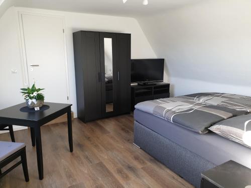 博霍尔特Ferienwohnung Berger Bocholt的一间卧室配有一张床、一张桌子和一台电视