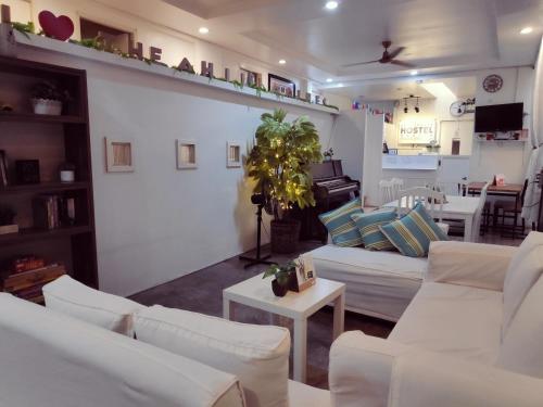 马尼拉Crossroads Hostel Manila的客厅配有白色沙发和钢琴