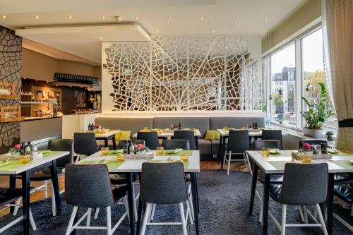 斯图加特斯特伽特城中心美居酒店的餐厅设有桌椅和大窗户。