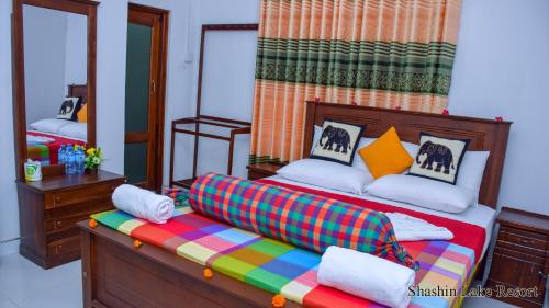 丹不拉Shashin Lake Resort的一间卧室配有一张带彩色毯子的床