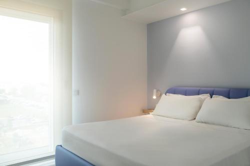 朱利亚诺瓦YOUMAMI Suite Hotel的白色的床、白色枕头和窗户