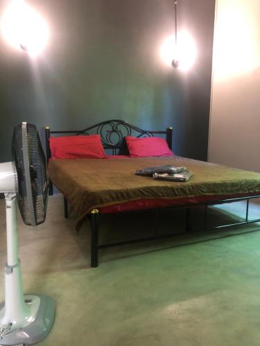 麦岛BP cheap private rooms的一间卧室配有一张带红色枕头的床和风扇