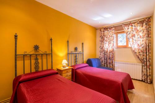 圣莱奥纳尔多德阿格Fuente del Pino Cañón de Río Lobos的黄色客房的两张床,配有红色床单