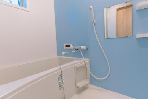 大阪暁 Twilight Osaka Inn的带淋浴的浴室,拥有蓝色的墙壁