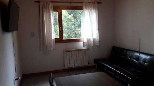 圣卡洛斯-德巴里洛切Departamento Victoria Bariloche的客厅配有黑色真皮沙发和窗户