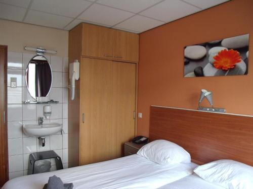 海滨诺德韦克杜恩鲁斯特佐恩酒店的一间卧室配有床、水槽和床 ⁇ 。