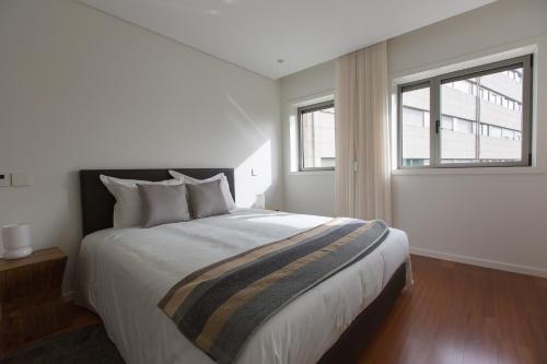 布拉加Braga Luxury Residence 3854的一间卧室设有一张大床和两个窗户。