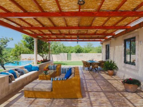 西利皮Villa Antonija的一个带沙发和椅子的庭院,位于木制凉棚下