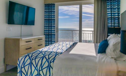 圣徒皮特海滩Provident Oceana Beachfront Suites的一间卧室配有一张床、一台电视和一个阳台