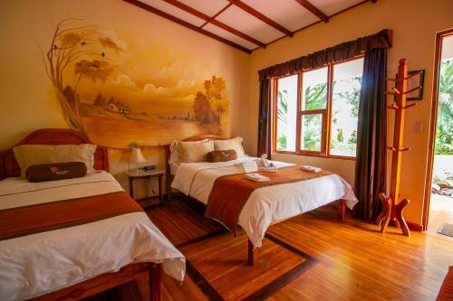 阿拉胡埃拉阿美利卡拉罗萨德酒店的一间卧室设有两张床,墙上挂着一幅画