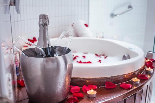 阿拉卡茹里尔经典酒店的浴室设有浴缸,提供一瓶香槟和红玫瑰