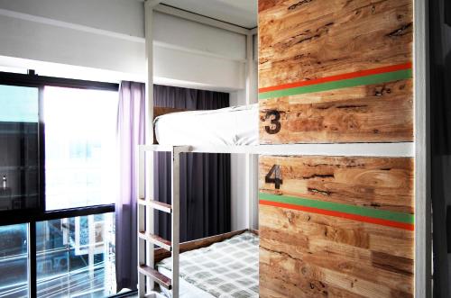 清迈绿色睡眠旅舍的一间卧室设有一张双层床和木墙