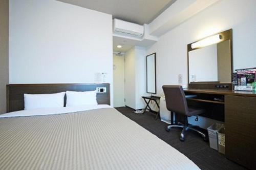 由利本庄市由利本庄路线酒店的酒店客房带一张床、一张书桌和一面镜子