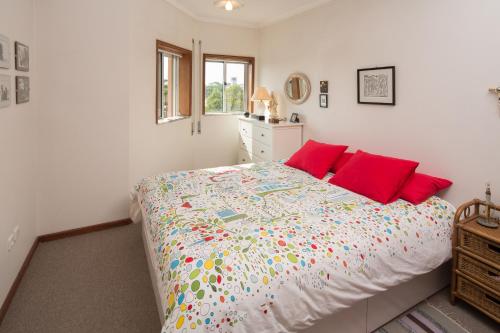 普拉亚达巴拉Barra Beach House - Praia da Barra的一间卧室配有一张带红色枕头的大床