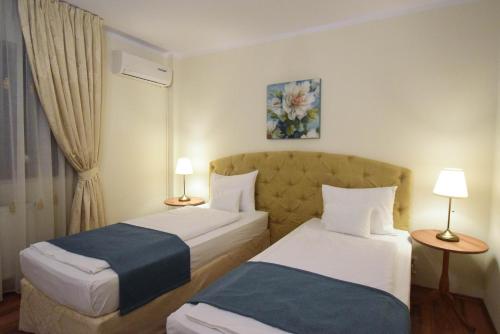 克卢日-纳波卡Cabrio Apart Hotel的酒店客房设有两张床和两盏灯。