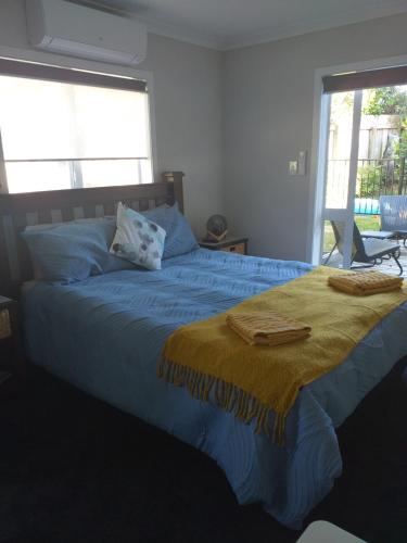 罗托鲁瓦Sleepout Hideaway的一间卧室配有一张蓝色的床和黄色的毯子