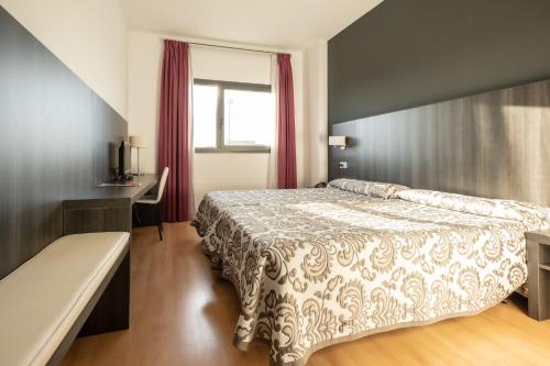 米兰达德埃布罗Hotel Abades Via Norte的一间卧室配有一张床、一张书桌和一个窗户。