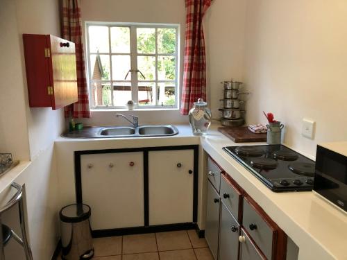 德尔斯特鲁姆Peace Corner Cottages的厨房配有水槽、炉灶和窗户。
