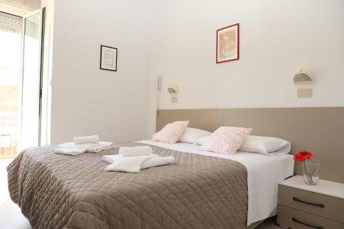 里米尼Hotel A Casa Nostra的卧室配有带粉色和白色枕头的大床