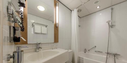赫尔桑姆Fletcher Hotel-Restaurant Klein Zwitserland的带浴缸、水槽和镜子的浴室