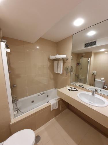 马亚中央公园酒店的一间带水槽、浴缸和卫生间的浴室
