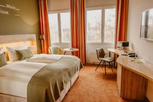 朗道因德普法尔茨朗达公园酒店的卧室配有一张床、一张书桌和窗户。